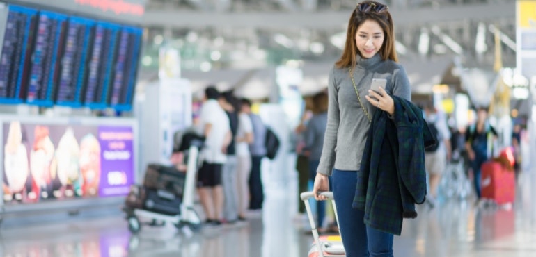 International roaming woman using phone at airport