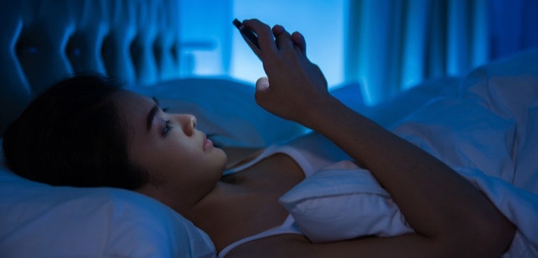Using phone in bed blue light health hero image